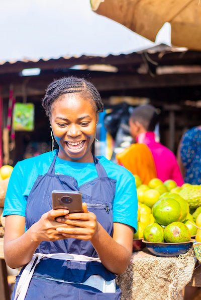 Female market trader using a mobile phone at a local market stall