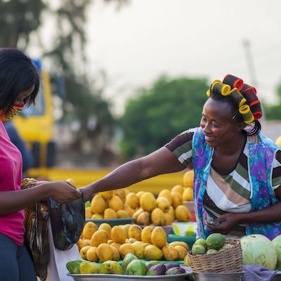 African saleswoman at a fruit stand with folded arms, confident and ready to trade